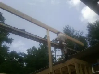 Carpenter setting a ridge beam over a new addition frame — Ice Dam Removal by Roofing Brothers in Saginaw