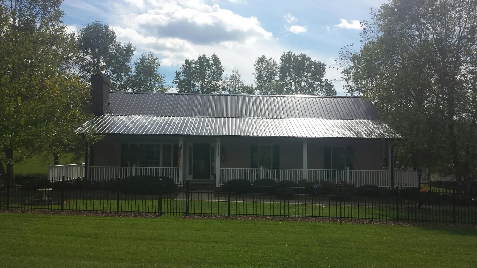Gray metal roof on a brick ranch with a full width front porch — Gutter Guard Installation work by our crew in Saginaw