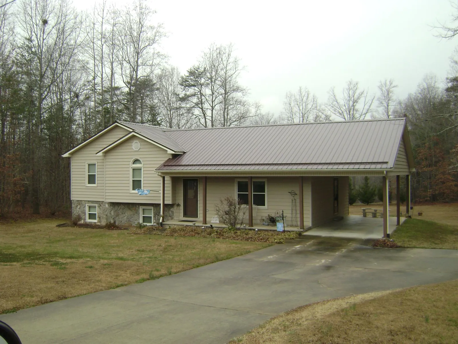 Brown metal roof on a tan split level home with an attached carport in Saginaw